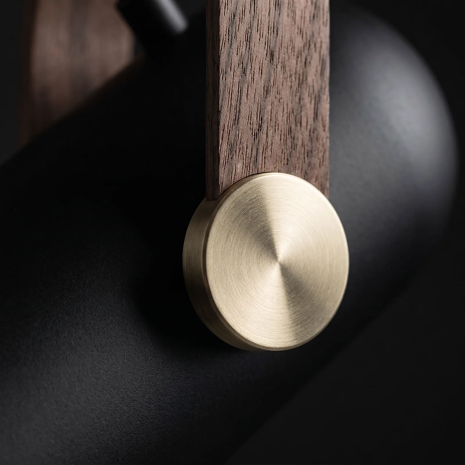 The brushed-brass pivot disc and walnut-grain strap, close up